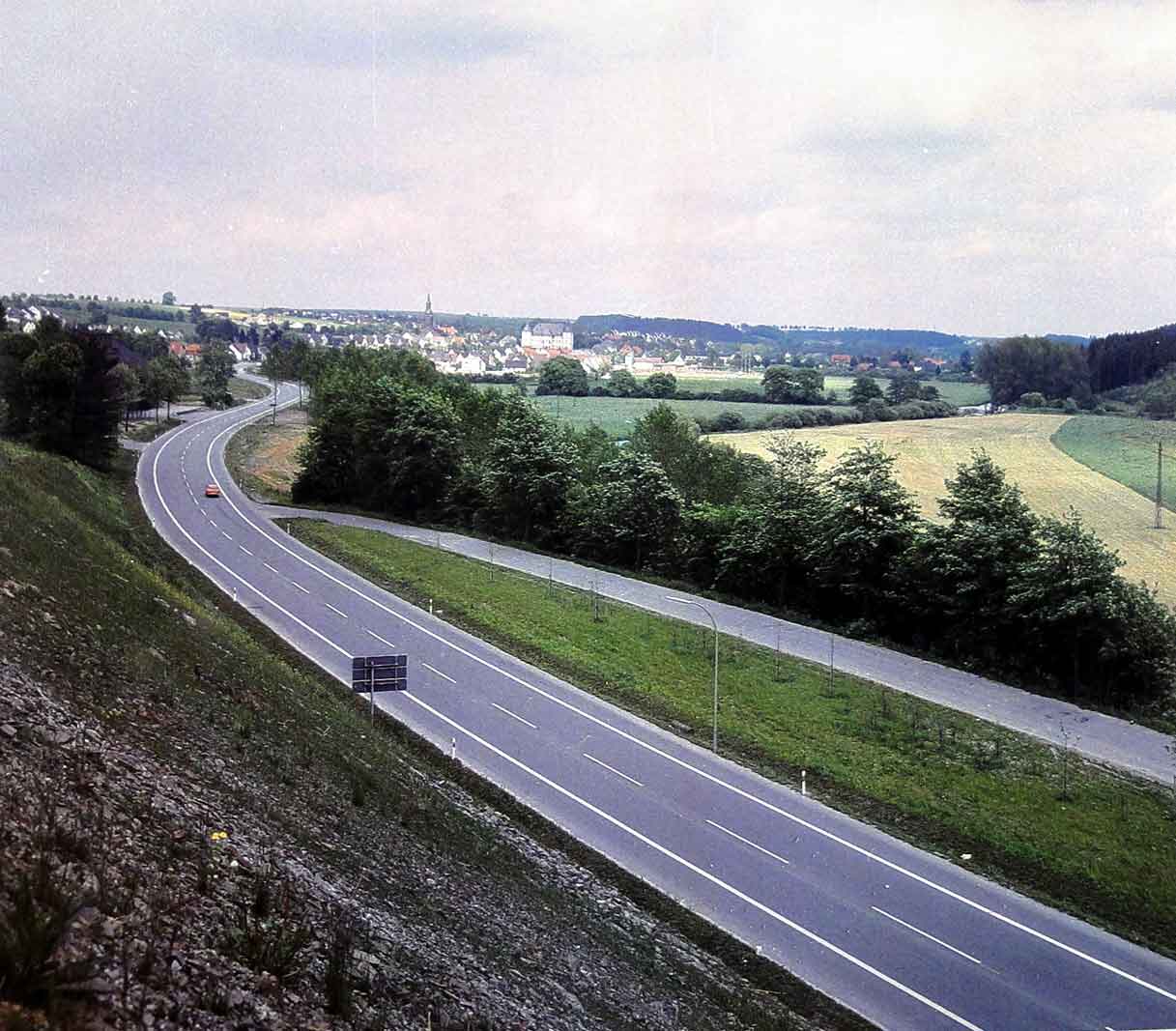 Blick ins Möhnetal / Von dem abgetragenen Hang bei Westendorf entstand um 1975 diese Aufnahme mit Blick auf die neue Möhnestraße B516. Gut zu erkennen ist rechts die alte Möhnestraße, die heute als Parkplatz genutzt wird. Die Kirche und das Kloster im Hintergrund strahlen im Licht der Sonne. Blick ins Möhnetal / Von dem abgetragenen Hang bei Westendorf entstand um 1975 diese Aufnahme mit Blick auf die neue Möhnestraße B516. Gut zu erkennen ist rechts die alte Möhnestraße, die heute als Parkplatz genutzt wird. Die Kirche und das Kloster im Hintergrund strahlen im Licht der Sonne.